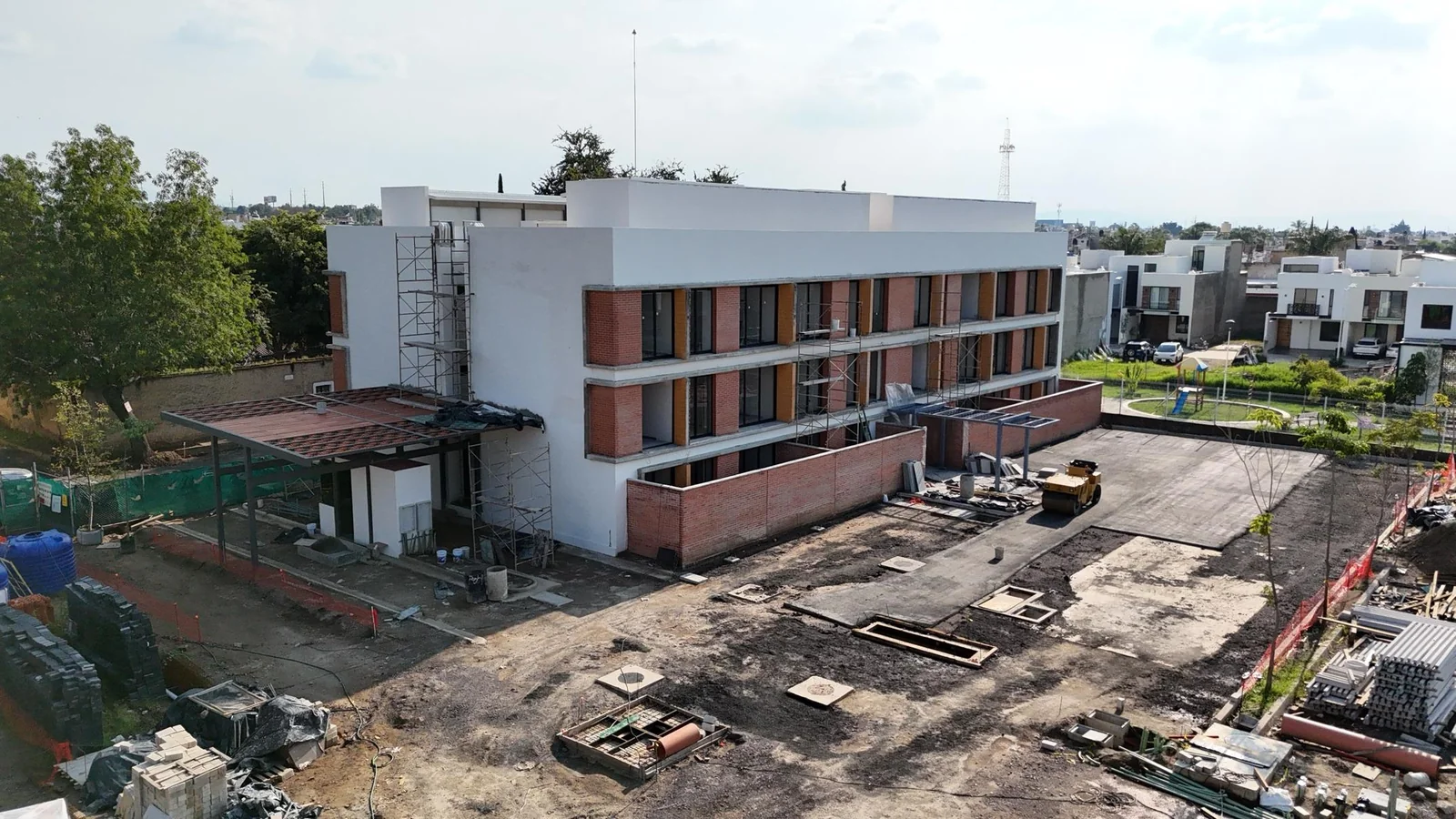 Torre 1 con la pérgola de acceso terminada y el estacionamiento en preparación