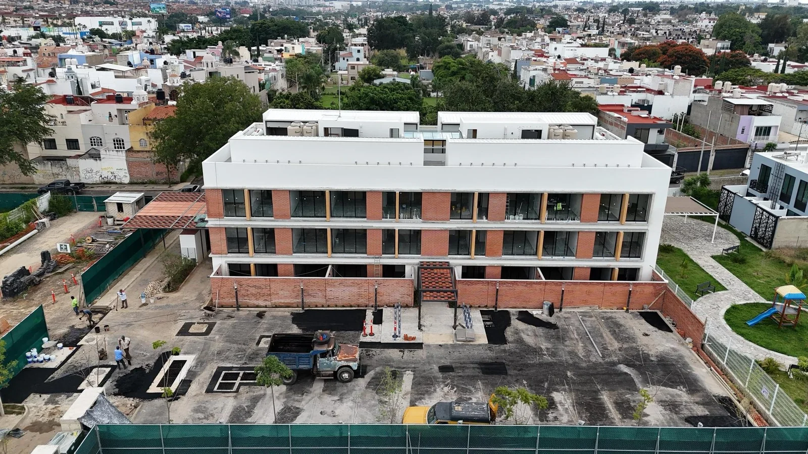 Fachada completa de la Torre 1 terminada, con el estacionamiento en pavimentación